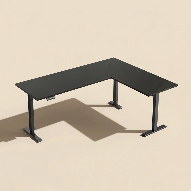Modern black OffiGo L-shaped standing desk with spacious corner workspace and adjustable sit-stand frame.