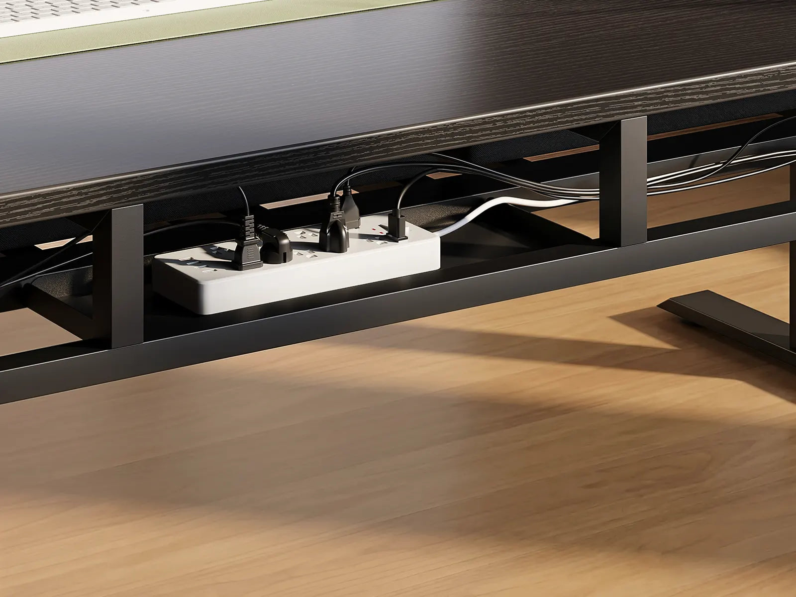 Black cable management tray mounted under a black standing desk, neatly organizing multiple wires and plugs.
