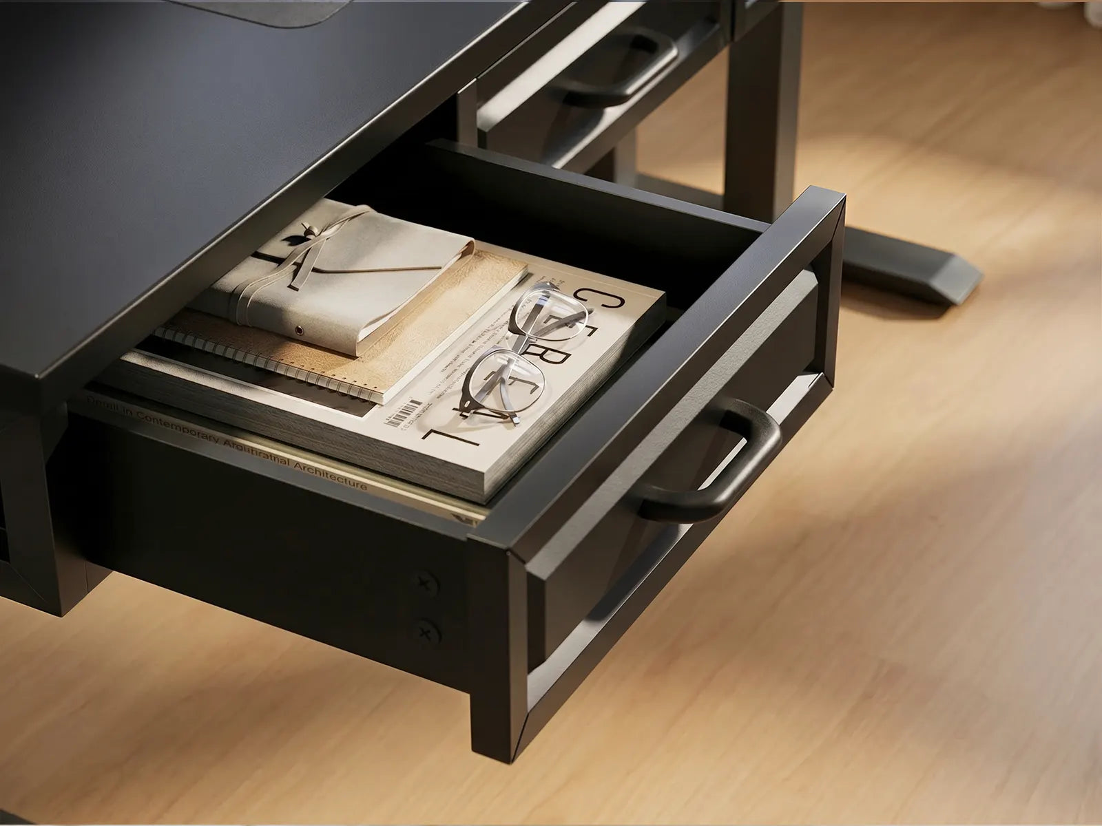 Black drawer under a desk, holding notebooks, glasses, and magazines, partially opened in a home office setup.