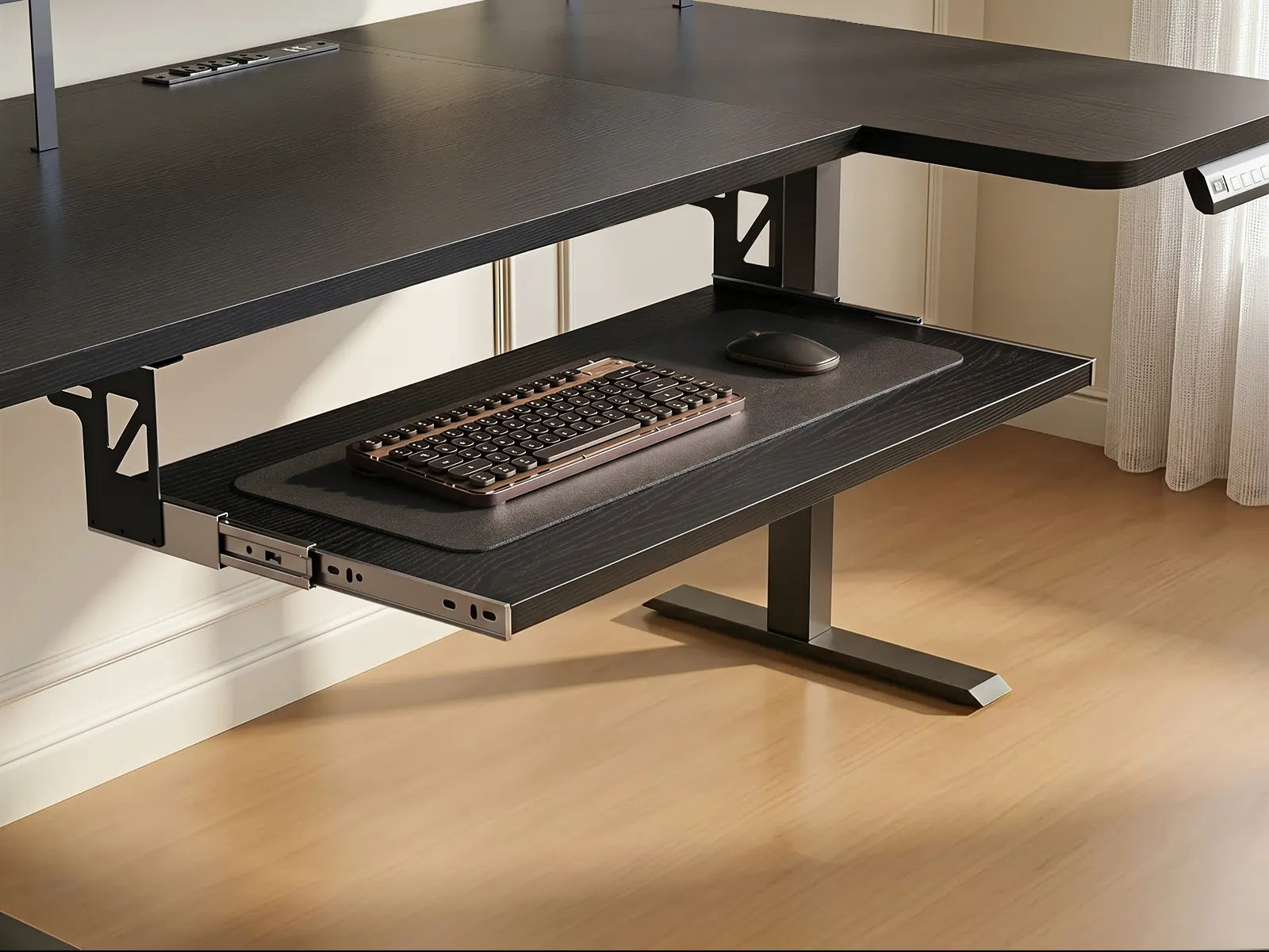 Black pull-out keyboard tray attached under a black standing desk, with a keyboard and mouse in place.