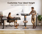 Seated and standing users at the OffiGo black L-shaped electric standing desk, illustrating the 28.4 to 45.7-inch height adjustment range.
