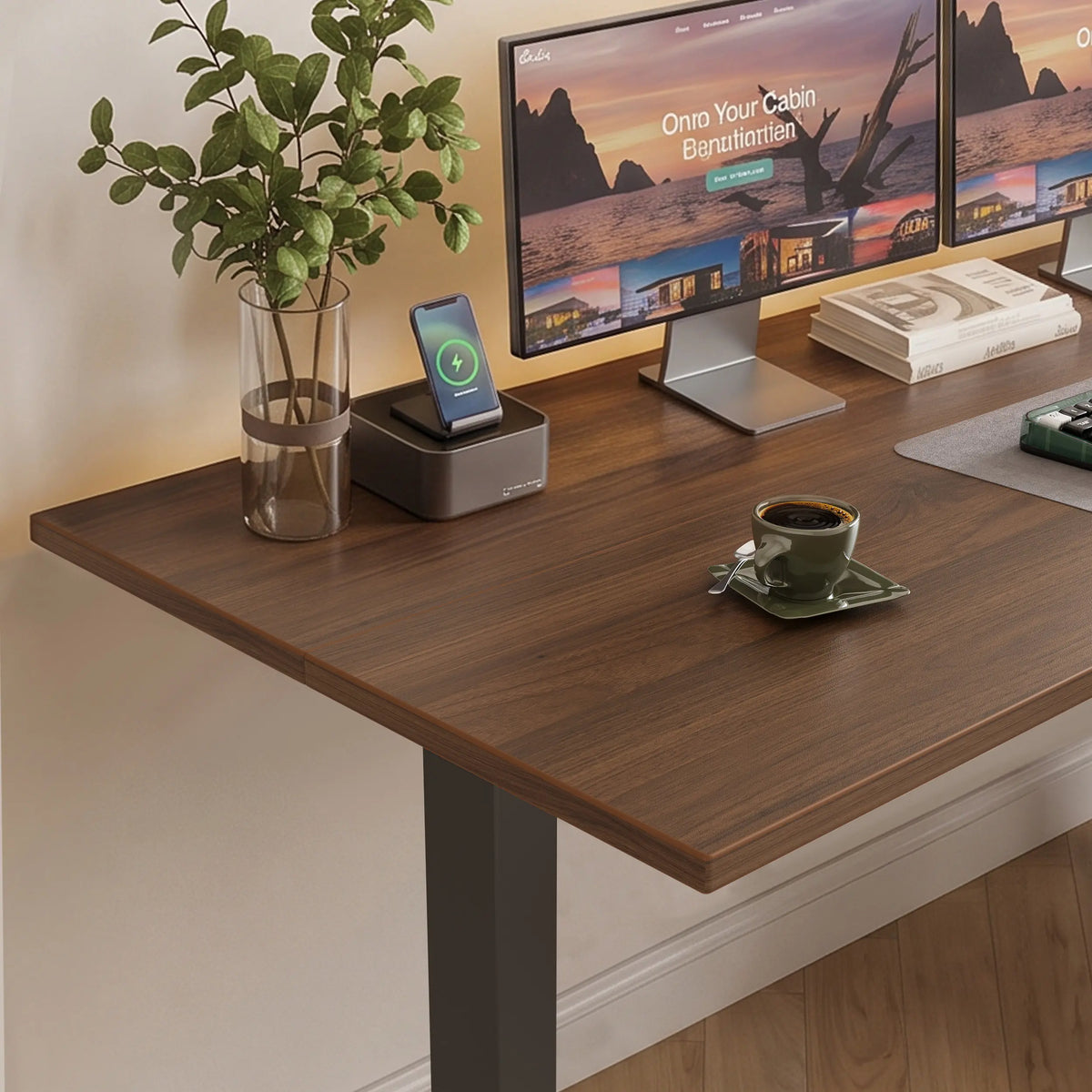 Close-up of an OffiGo wood-grain desktop and edge, with monitors, a phone charging stand, a vase, and a coffee cup.