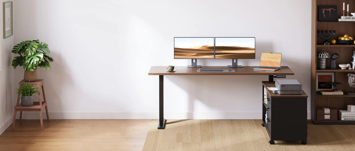 OffiGo wood-look standing desk with dual monitors and a laptop, paired with a black rolling file cabinet and printer in a home office.